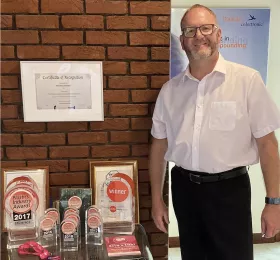 Karl Miller in front of the company's numerous awards